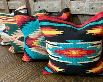 May include: Four decorative throw pillows with a southwestern geometric pattern in shades of black, turquoise, red, yellow, and white.