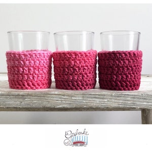 Könnte beinhalten: Drei Glasbecher mit gehäkelten Bechern in Rosa, Rot und Lila. Die Bezüge sind mit einem Farbverlauf gearbeitet.