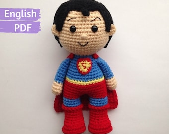 Peut inclure: Poupée Superman en crochet avec une cape rouge, un costume bleu et une ceinture jaune. La poupée a les cheveux noirs, un visage brun et un grand sourire.
