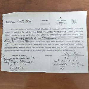 May include: A vintage Turkish document from 1936, featuring handwritten text in Turkish. The document includes details such as a date, number, and monetary values in Turkish Lira and Kurus. The paper has aged, with visible creases and wear.