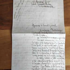 May include: A vintage handwritten letter on aged paper, featuring elegant cursive script in black ink. The document is folded and appears to be a formal correspondence, with text in French. The paper has a slightly yellowed hue, suggesting age.