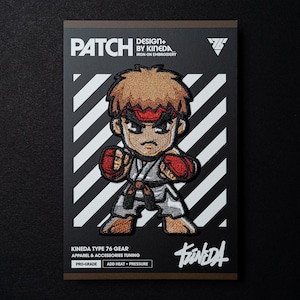 May include: Iron-on embroidered patch featuring a cartoon character in a white karate uniform with a red headband. The character has brown hair and is in a fighting stance. The patch is on a white and black striped background with the text "PATCH DESIGN+ BY KINEDA IRON-ON EMBROIDERY" at the top and "KINEDA TYPE 76 GEAR APPAREL & ACCESSORIES TUNING PRO-GRADE ADD HEAT + PRESSURE" at the bottom.