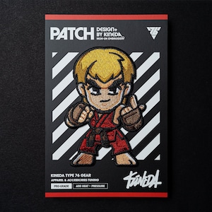 Może przedstawiać: Naszywka do prasowania z haftem przedstawiająca postać z kreskówki w czerwonym stroju karate z żółtym pasem. Naszywka znajduje się na biało-czarnym paskowanym tle z tekstem "DESIGN+ BY KIMEDA IRON-ON EMBROIDERY" i "KINEDA TYPE 76 GEAR APPAREL & ACCESSORIES TUNING" pod postacią. Tekst "PRO-GRADE ADD HEAT + PRESSURE" znajduje się na dole naszywki.