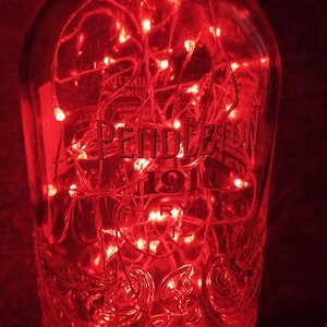 May include: A glass bottle with a red light string inside. The bottle is labeled "Pendleton 1910 Rye".