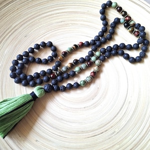 May include: A black lava stone mala necklace with green, brown, and red beads and a green tassel.