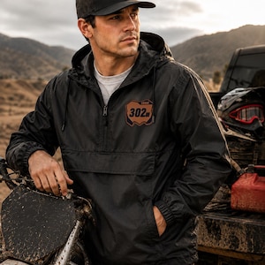 Personalized motocross windbreaker with custom leatherette number plate patch featuring your name and race number on a black lightweight riding jacket.
