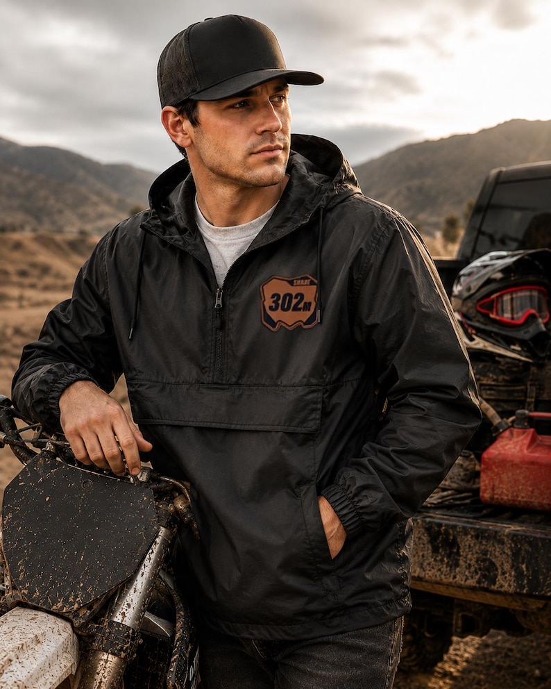 Personalized motocross windbreaker with custom leatherette number plate patch featuring your name and race number on a black lightweight riding jacket.