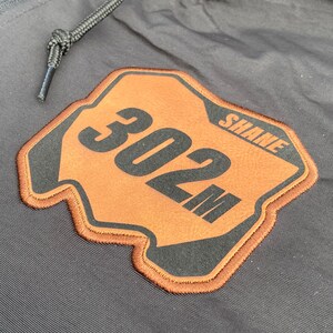 Close-up view of the laser engraved leatherette motocross number plate patch professionally embroidered onto the windbreaker.