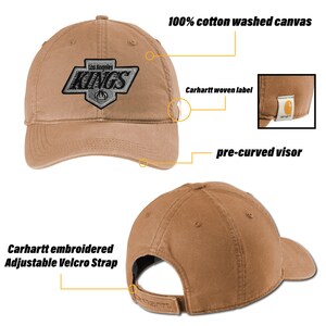 K&ouml;nnte beinhalten: Eine braune Baseballkappe mit einem vorgekr&uuml;mmten Visier. Die Kappe hat ein gesticktes Carhartt-Logo auf der R&uuml;ckseite und ein gesticktes Los Angeles Kings-Logo auf der Vorderseite. Die Kappe ist aus 100% gewaschener Baumwoll-Canvas gefertigt und hat einen verstellbaren Klettverschluss.