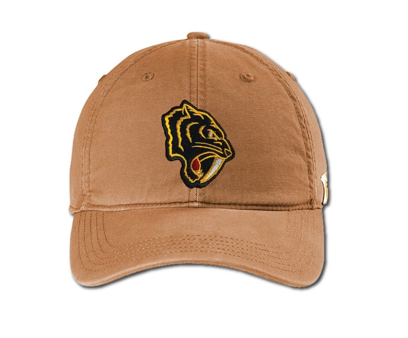 Puede incluir: Una gorra de b&eacute;isbol marr&oacute;n con una imagen bordada en negro y dorado de un tigre dientes de sable en la parte delantera.