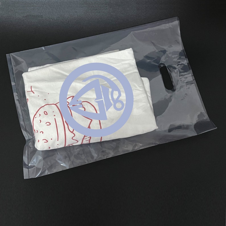 May include: A white t-shirt with a red and white graphic of a burger and a blue circle with a red graphic inside. The t-shirt is in a clear plastic bag with a handle.