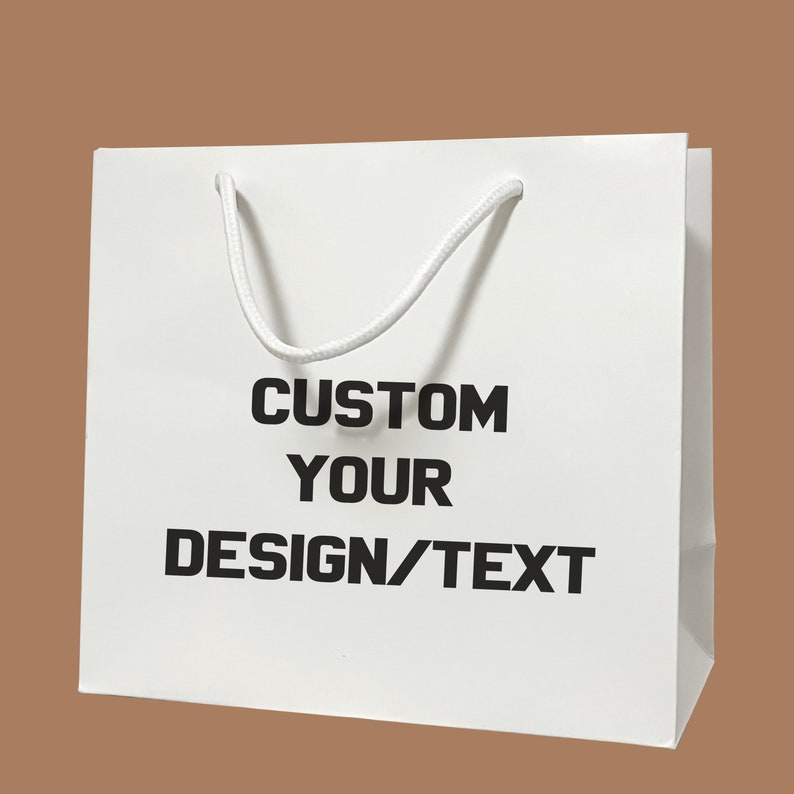 Puede incluir: Bolsa de regalo de papel blanco con asa de cuerda blanca. La bolsa tiene texto negro que dice "CUSTOM YOUR DESIGN/TEXT".