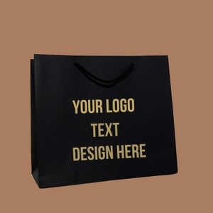 Puede incluir: Bolsa de papel negra con texto dorado que dice "YOUR LOGO TEXT DESIGN HERE".