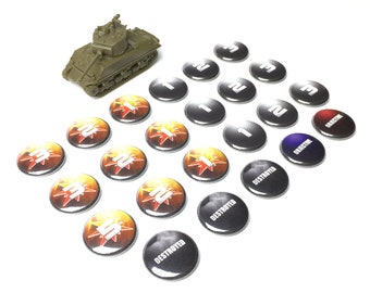 May include: A green toy tank with a black base and a white number 1 on the side. There are 15 round tokens with various designs, including numbers, the word "Destroyed", and the word "Objective".