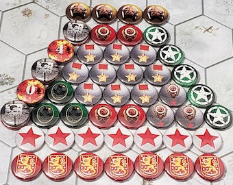May include: A collection of game pieces for a board game. The pieces are round and feature various designs, including stars, numbers, and symbols. The pieces are arranged in a triangular pattern on a white surface.