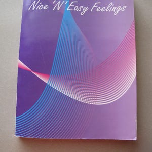 May include: Purple book cover with the title "Nice 'N Easy Feelings" in white text. The cover features a blue and pink abstract design with curved lines.