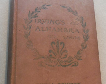 May include: A brown book with the title "Irving's Alhambra" by Washington Irving. The book is part of the "Home and School Library" series and published by Ginn & Company.