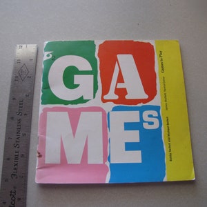 May include: A yellow, green, pink, red, and blue book cover with the word "GAMES" in large, white letters. The book title is "Games to Play" and the authors are listed as "Babby Seifert and Michael Seifert" and "James Motlett, Senior Editor".