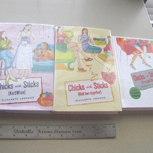 May include: Three books titled "Chicks with Sticks" are displayed, each with a different cover illustration of women knitting. The books are in shades of pink, yellow, and white. A Westcott ruler, approximately 12 inches long, is at the bottom.