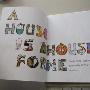 May include: Open book with the title "A House Is Home" in colorful, illustrated letters. The book's text is by Mary Ann Hoberman and illustrated by Betty Fraser. The letters are decorated with images of a tent, house, ice cream cone, and more.
