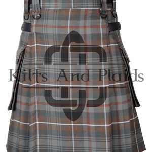 May include: A brown, grey and white tartan kilt with a leather strap and buckle detail. The kilt has two large cargo pockets on the sides.