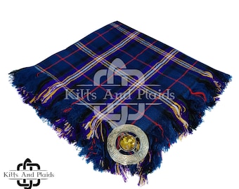 May include: A navy blue tartan scarf with a fringed edge and a decorative silver brooch. The scarf features a plaid pattern with red, yellow, and white lines. The brooch has an ornate design and a central yellow stone.