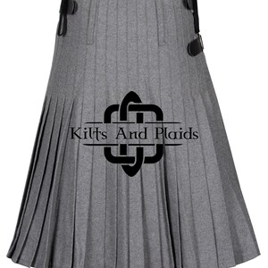 May include: A gray kilt with pleats and a black leather strap. The kilt has a black logo that says "Kilts And Plaids".