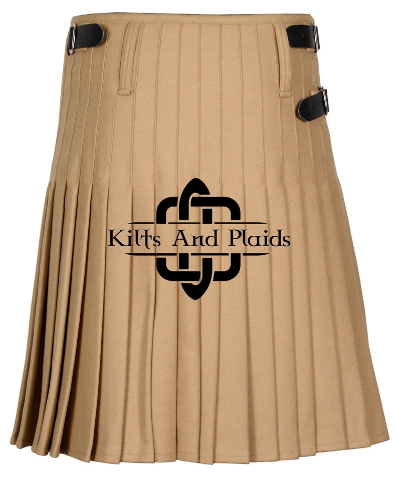May include: A tan kilt with black buckles and pleats. The kilt has a black logo with the text "Kilts And Plaids" on it.