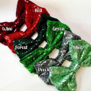 May include: A selection of sequined headbands in shades of red, forest green, green, mint, and pewter. Each headband is embellished with sparkling sequins and has a label indicating its colour.