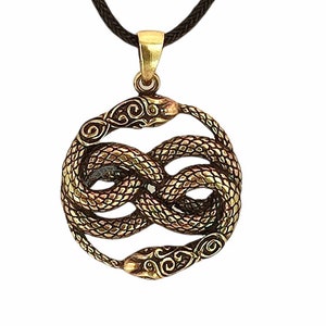 Könnte beinhalten: Ein bronzefarbener Metallanhänger in Form von zwei ineinander verschlungenen Schlangen, die eine Unendlichkeitsschleife bilden, an einem dunkelbraunen geflochtenen Band. Die Schlangen zeigen detaillierte Schuppen und Verzierungen.