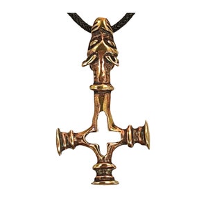 May include: A bronze pendant with a cross design and a wolf's head at the top. The pendant is on a black cord.