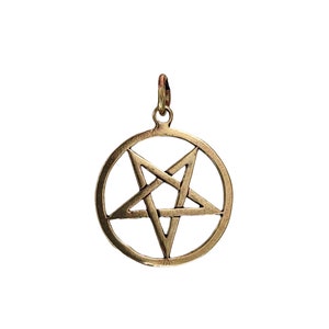 Puede incluir: Un colgante dorado con un pentagrama, o estrella de cinco puntas, dentro de un círculo. El colgante está hecho de metal y tiene un diseño simple y elegante.