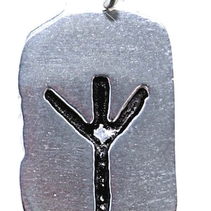 Puede incluir: Un amuleto de plata con un s&iacute;mbolo negro estilizado de cuatro puntas.