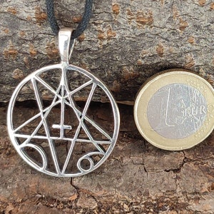 May include: Silver pendant necklace featuring a pentagram with a cross inside, surrounded by a circle. The pendant is about the size of a Euro coin.