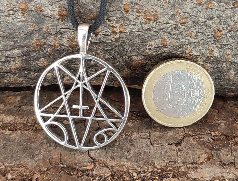 May include: Silver pendant necklace featuring a pentagram with a cross inside, surrounded by a circle. The pendant is about the size of a Euro coin.