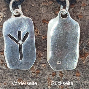 Puede incluir: Colgante de plata con un s&iacute;mbolo de runa en la parte delantera y un sello 925 en la parte posterior. El colgante est&aacute; en un cord&oacute;n negro.
