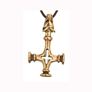 May include: A gold-toned pendant in the shape of a cross with a wolf's head at the top. The cross has a circular opening in the center.