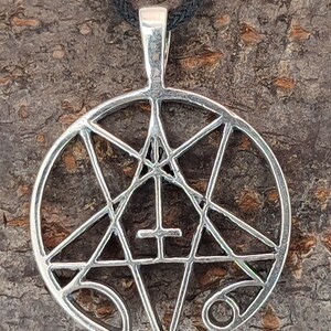 May include: A silver pendant necklace with a pentagram design. The pentagram is surrounded by a circle and has a cross in the center.