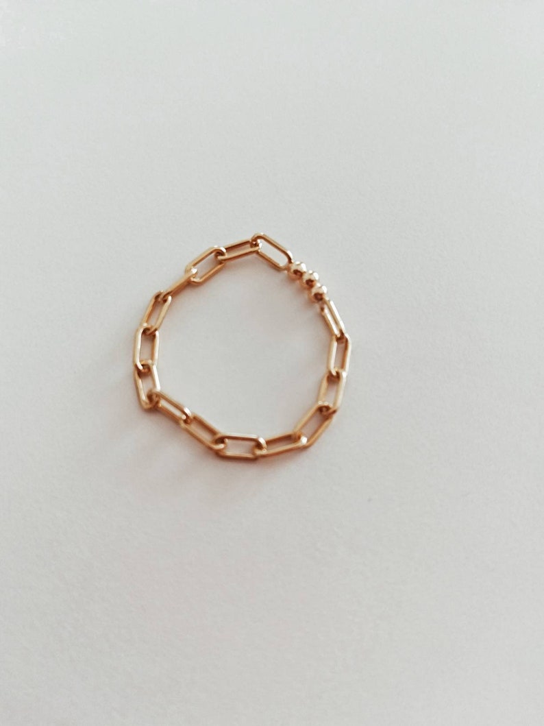 Puede incluir: Un anillo de cadena de oro con un peque&ntilde;o acento de cuentas.