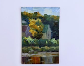 May include: An oil painting on a rectangular canvas depicting a landscape with a house nestled among trees. The scene features a bright yellow tree, dark green foliage, and a light blue sky. The lower portion shows a reflective body of water.