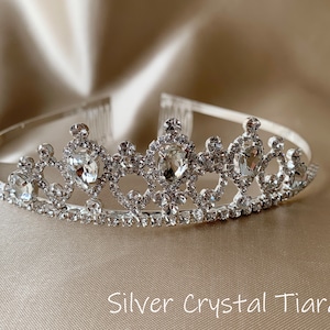 Pode incluir: Uma tiara prateada com detalhes de cristal transparente. A tiara tem um pente na parte de tr&aacute;s para f&aacute;cil fixa&ccedil;&atilde;o no cabelo.
