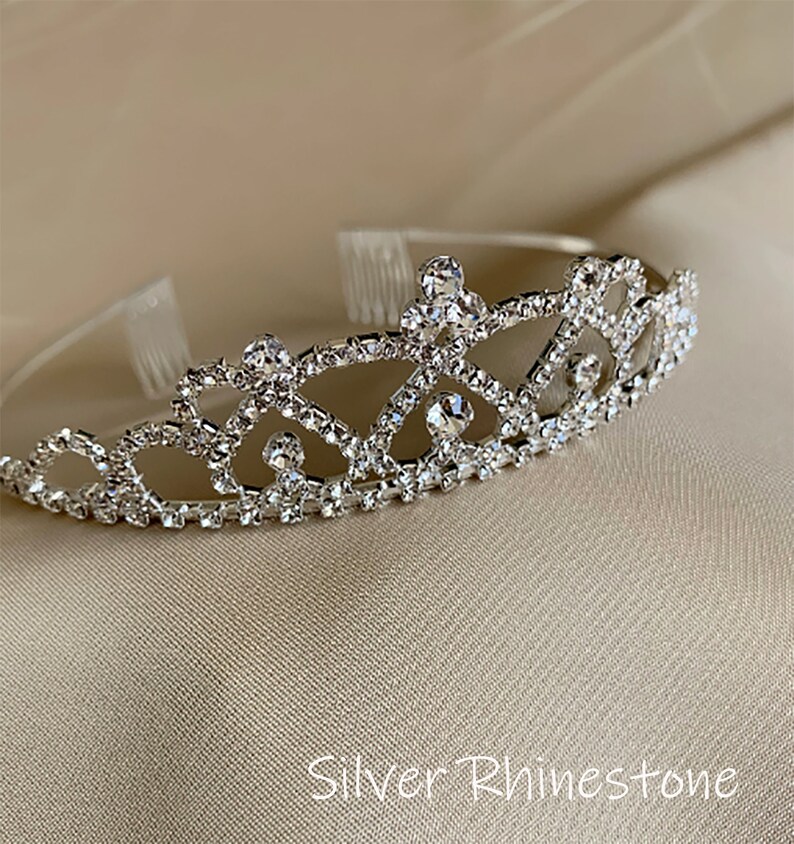 Pode incluir: Uma tiara prateada com strass transparentes. A tiara tem um design delicado e &eacute; perfeita para uma princesa.