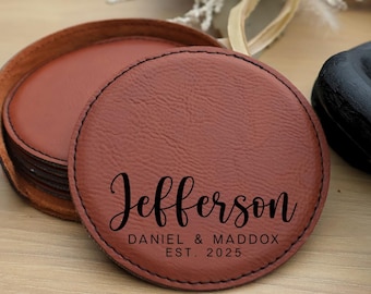 Könnte beinhalten: Satz mit sechs braunen Lederuntersetzern mit genähten Kanten. Der oberste Untersetzer trägt den Text "Jefferson Daniel & Maddox Est. 2025" in Schwarz.