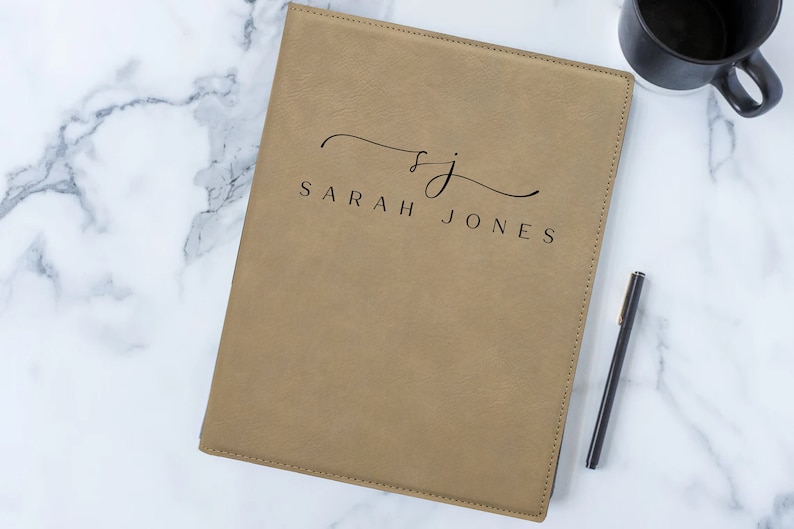 May include: A tan leather folder with the initials "SJ" and the name "SARAH JONES" embossed in black.