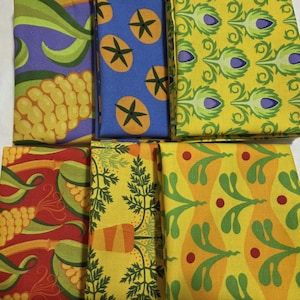 May include: A collection of folded fabric pieces with various colorful patterns. Designs include corn, star-shaped fruit, peacock feathers, and other botanical motifs. The fabrics feature a mix of colors, including yellow, blue, red, and purple.