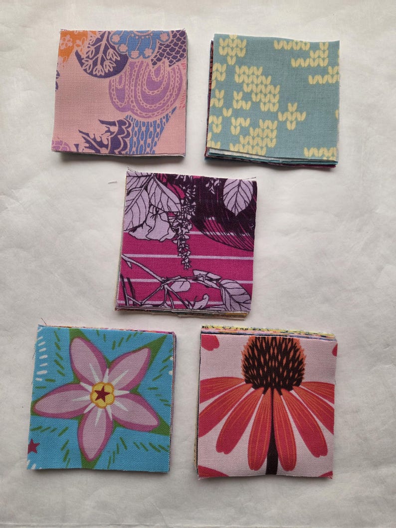 May include: Five stacks of square fabric swatches featuring various patterns. The top swatches display a pink floral print, a light blue knit-style pattern, a dark magenta botanical design, a blue flower with a star center, and a large orange coneflower.