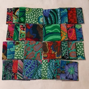 Könnte beinhalten: Eine Sammlung farbenfroher Stoffquadrate mit verschiedenen floralen und abstrakten Mustern. Die Quadrate weisen Farbtöne von Grün, Blau, Rot und Rosa auf. Die Stoffdesigns umfassen Paisley, Blätter und andere botanische Motive.