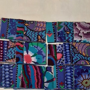 Può includere: Una collezione di piccoli pezzi di tessuto quadrati con disegni astratti vibranti. La tavolozza dei colori comprende sfumature di blu, viola, verde e rosa. Alcuni quadrati presentano motivi di uccelli e fiori, altri motivi geometrici.