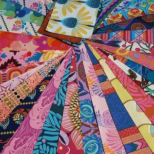 May include: A fan of colorful fabric swatches with various floral and geometric patterns. The fabrics feature shades of pink, blue, yellow, and green. The image is a close-up, showcasing the intricate designs and textures of the textiles.