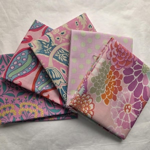Könnte beinhalten: Eine Sammlung gefalteter Stoffquadrate in verschiedenen floralen und gemusterten Designs. Die Stoffe weisen rosa, grüne, blaue und orange Farbtöne auf. Ein Stoff hat einen großen Blumendruck, während andere Paisley- und Polka-Dot-Muster aufweisen.